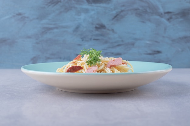 Foto grátis espaguete cozido com linguiças fatiadas na placa azul.