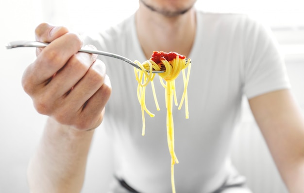 Espaguete saboroso de homem comendo com molho de tomate