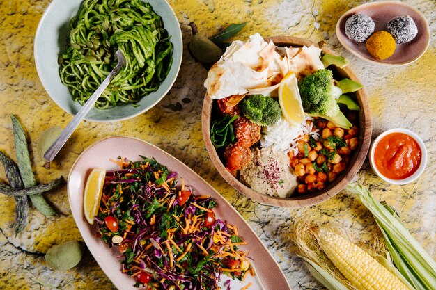 Espaguete, salada de legumes e prato principal, com legumes e biscoitos.