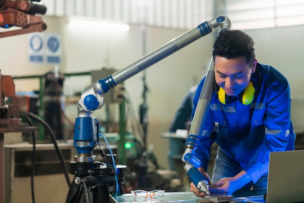 Especialista em engenheiro masculino asiático com máquina de medição com braço manipulador Medição de coordenadas tridimensionais Verifique os tamanhos Verificação 3D dos tamanhos das peças CMM após o processo de usinagem