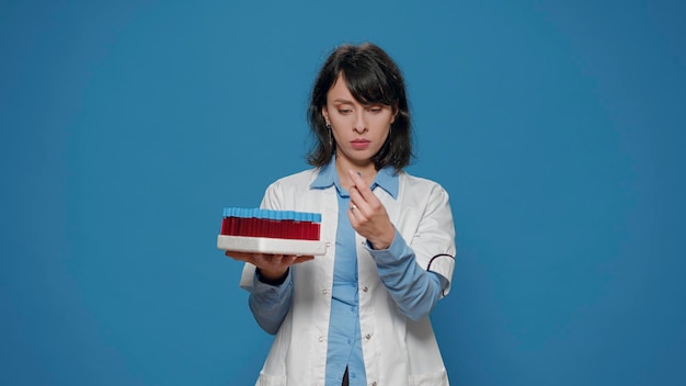 Foto grátis especialista em microbiologia olhando tubos de ensaio com amostras líquidas na bandeja, fazendo experimentos científicos para encontrar a cura farmacêutica. químico feminino usando vacutainers para analisar a substância.