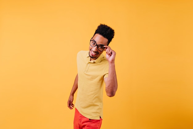 Espectacular homem inspirado em óculos posando. Cara Africano animado se divertindo.