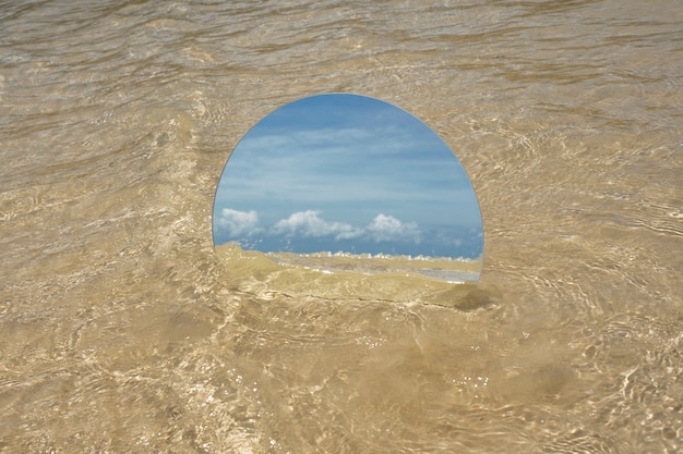 Espelho de vidro redondo na praia refletindo a paisagem