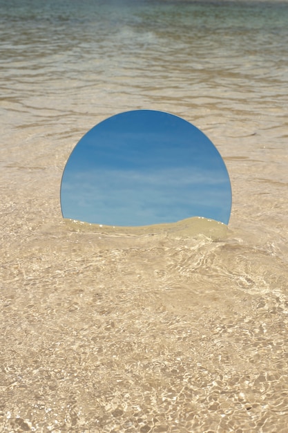 Espelho de vidro redondo na praia refletindo a paisagem