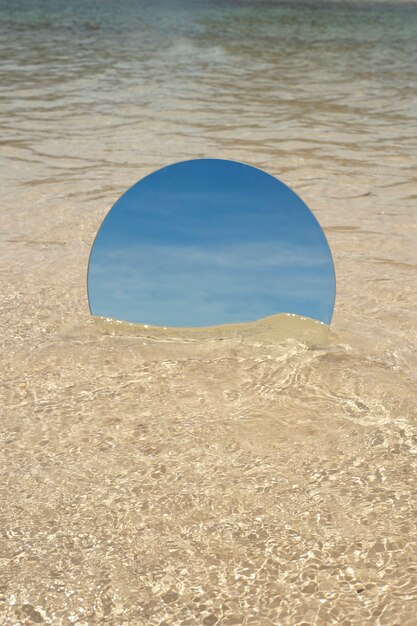 Espelho de vidro redondo na praia refletindo a paisagem