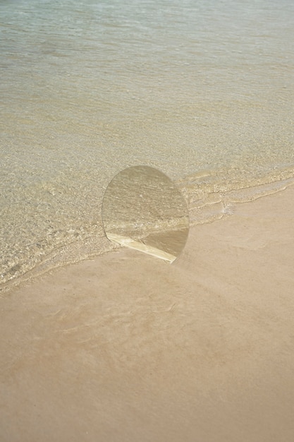 Espelho de vidro redondo na praia refletindo a paisagem