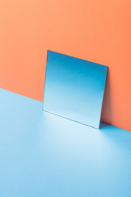 Espelho na mesa azul isolada na laranja