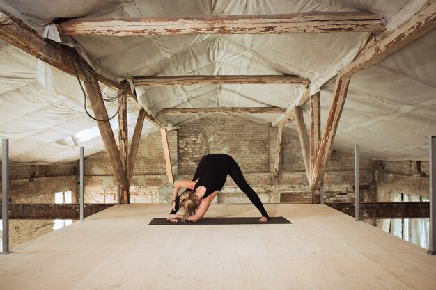 Espelho. Uma jovem mulher atlética exercita ioga em uma construção abandonada. Equilíbrio da saúde mental e física. Conceito de estilo de vida saudável, esporte, atividade, perda de peso, concentração.