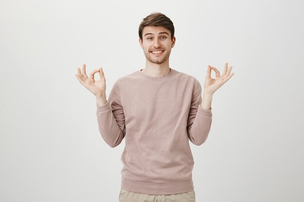 Esperançoso jovem bonito mostrar tudo bem, gesto zen