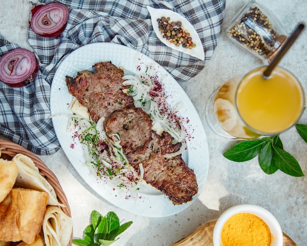 Espetada de carne caucasiano com salada de cebola e suco de laranja.