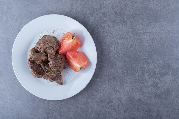 Espetada de carne grelhada e tomate na chapa branca.