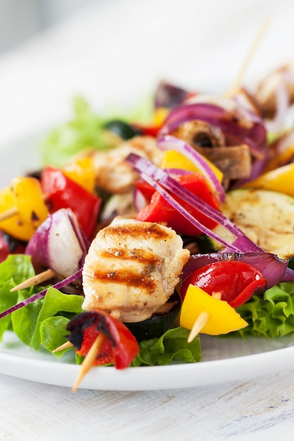 Espetos de frango com cebolas em cima de uma salada