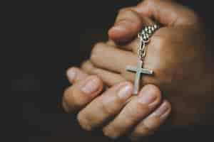 Foto grátis espiritualidade e religião, mulheres em conceitos religiosos mãos que praying ao deus ao prender o símbolo da cruz. freira pegou a cruz na mão.