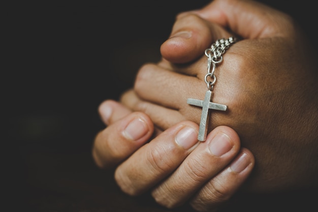 Espiritualidade e religião, mulheres em conceitos religiosos Mãos que praying ao deus ao prender o símbolo da cruz. Freira pegou a cruz na mão.