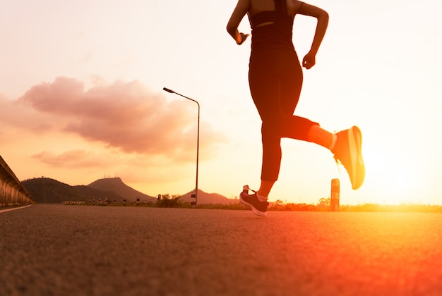 Esporte mulher correndo em uma estrada. fitness mulher treinando ao pôr do sol