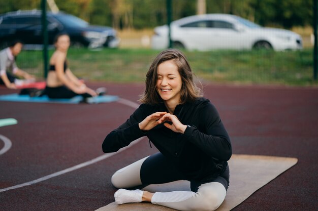 Esportes e fitness fora do ginásio. Jovem apta a mulher em trajes esportivos treina ao ar livre no playground.