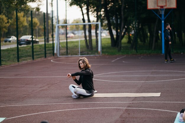 Esportes e fitness fora do ginásio. Jovem apta a mulher em trajes esportivos treina ao ar livre no playground.