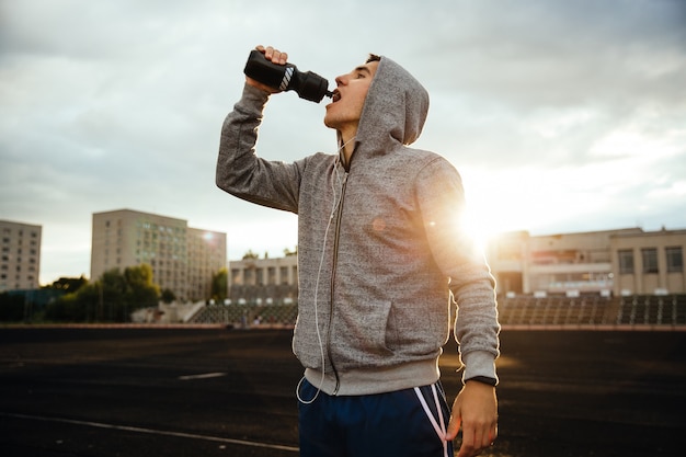 Foto grátis esportista bebendo água depois de correr, malhar, com fones de ouvido