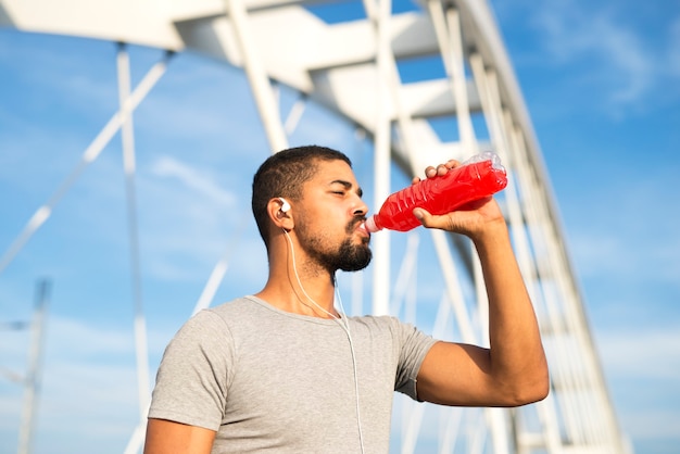 Esportista bebendo bebida energética refrescante após o treino hidratando o corpo