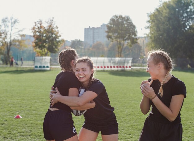 Esportivas meninas abraçando com uma bola de futebol