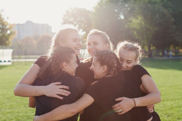 Esportivas mulheres abraçando em um campo de futebol