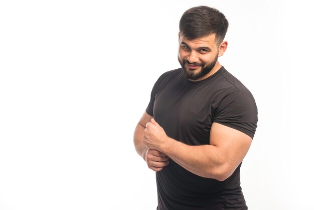 Esportivo homem de camisa preta, demonstrando os músculos do braço.