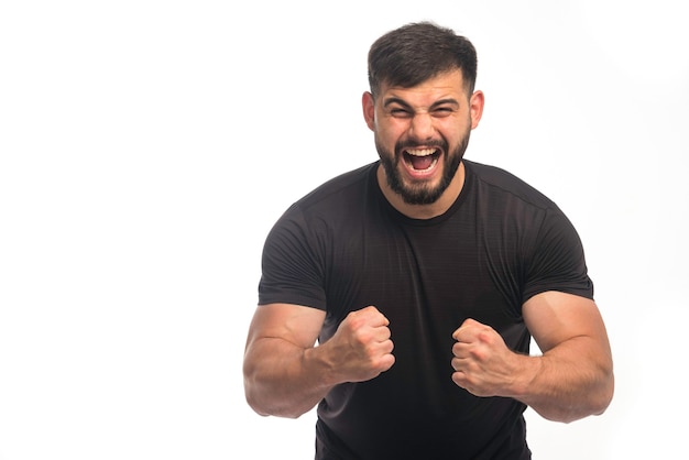 Esportivo homem de camisa preta, mostrando seu bíceps.