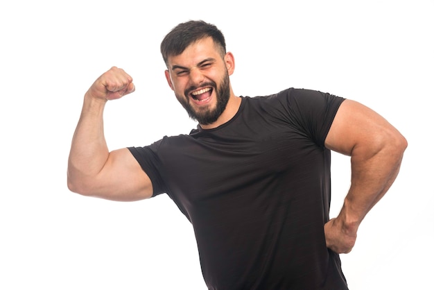 Esportivo homem de camisa preta, sentindo-se forte.