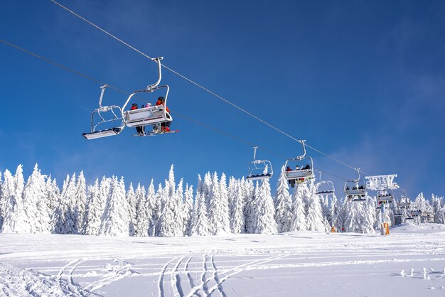 Esquiadores em um teleférico em um resort nas montanhas com céu e montanhas