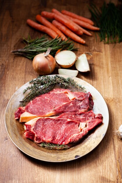 Estaca de carne crua com ervas e vegetais frescos prontos para serem grelhados. Ingrediente secreto. Proteína natural.