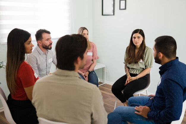 Estamos aqui por você. Diversas pessoas em um encontro anônimo alcoólico ouvindo a experiência com vício de um novo membro do grupo