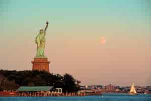 Foto grátis estátua da liberdade e lua cheia ao pôr do sol em nova york