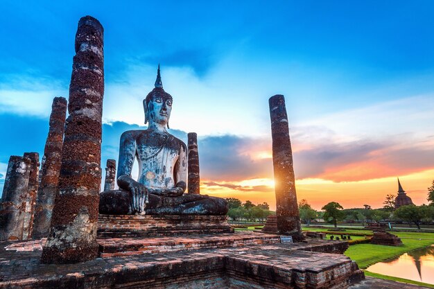 Estátua de Buda e templo Wat Mahathat no recinto do Parque Histórico de Sukhothai