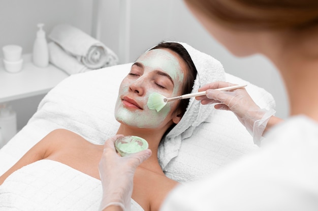 Esteticista aplicando máscara facial em cliente