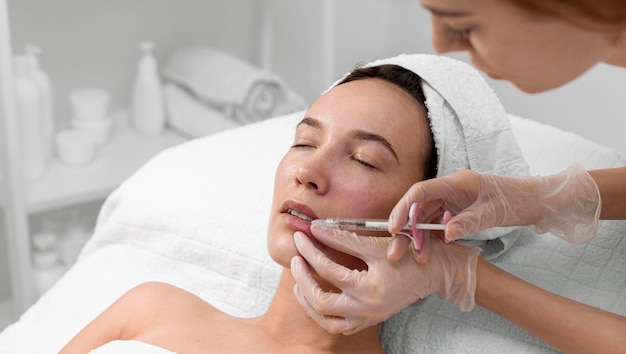 Esteticista aplicando preenchimento com injeção em cliente