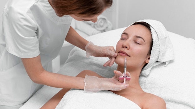 Esteticista aplicando preenchimento com injeção em cliente