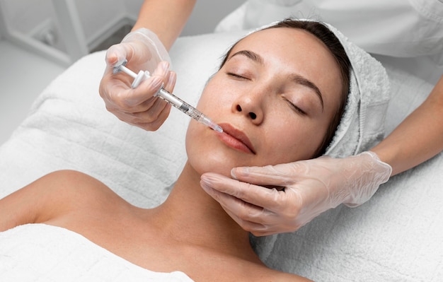 Esteticista aplicando preenchimento com injeção em cliente