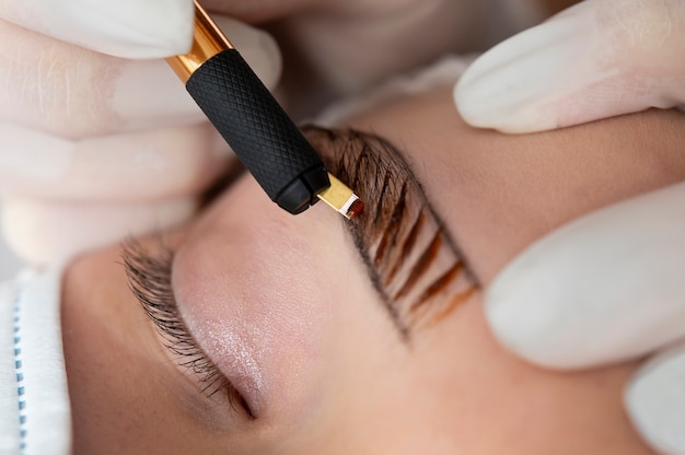 Esteticista fazendo um procedimento de microblading nas sobrancelhas de uma cliente