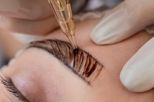 Esteticista fazendo um procedimento de microblading nas sobrancelhas de uma cliente