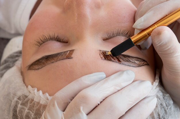 Esteticista fazendo um procedimento de microblading nas sobrancelhas de uma cliente