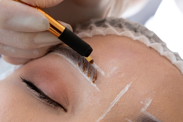 Esteticista fazendo um procedimento de microblading nas sobrancelhas de uma cliente