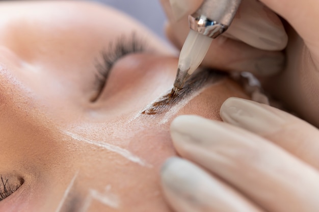 Esteticista fazendo um procedimento de microblading nas sobrancelhas de uma cliente