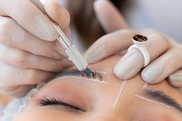 Esteticista fazendo um procedimento de microblading nas sobrancelhas de uma cliente