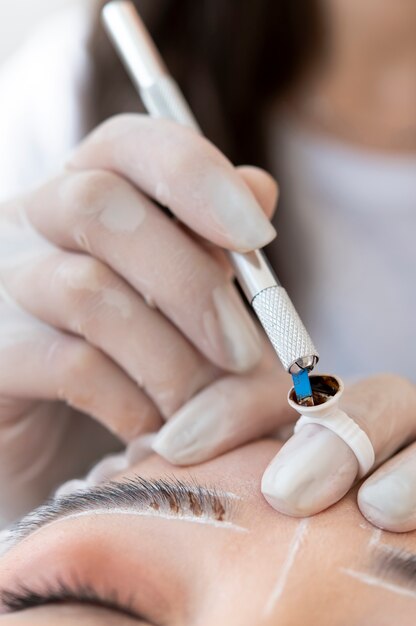 Esteticista fazendo um tratamento de microblading nas sobrancelhas de uma cliente