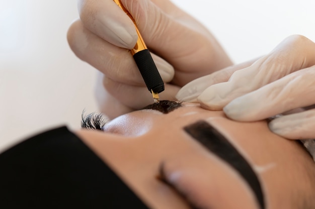 Esteticista fazendo um tratamento de microblading nas sobrancelhas de uma cliente