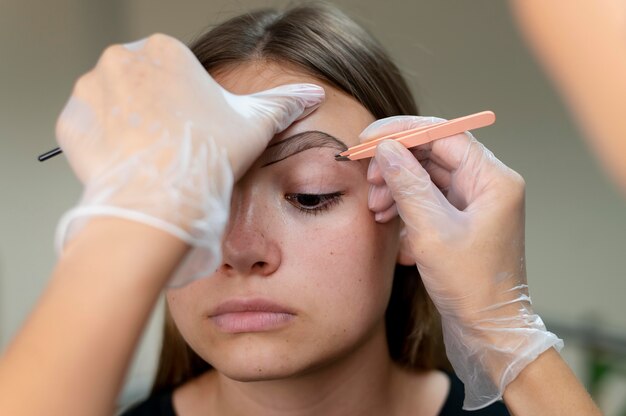 Esteticista realizando procedimento de microblading em uma jovem