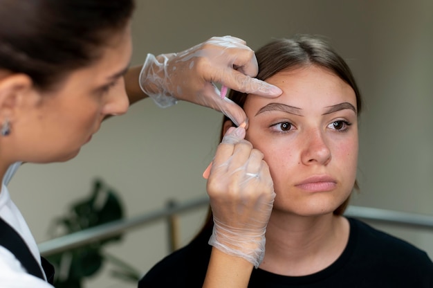 Esteticista realizando procedimento de microblading em uma jovem