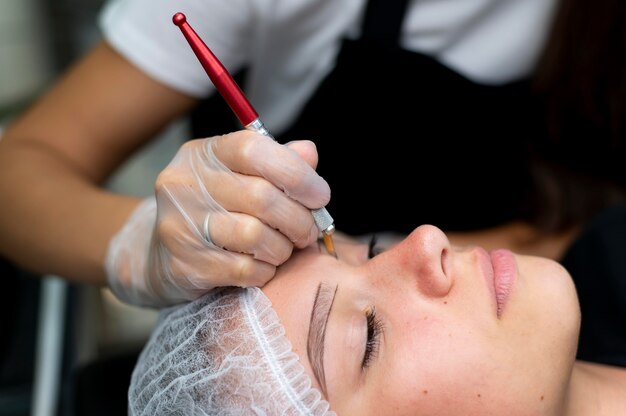 Esteticista realizando procedimento de microblading em uma jovem