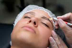 Foto grátis esteticista realizando procedimento de microblading em uma mulher em um salão de beleza