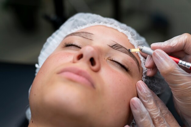 Esteticista realizando procedimento de microblading em uma mulher em um salão de beleza